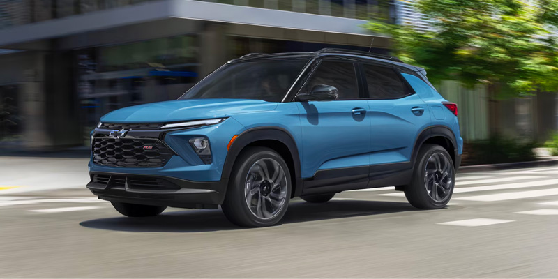 Front-three-quarter view of a bright blue Chevrolet Trailblazer RS driving down a city street.